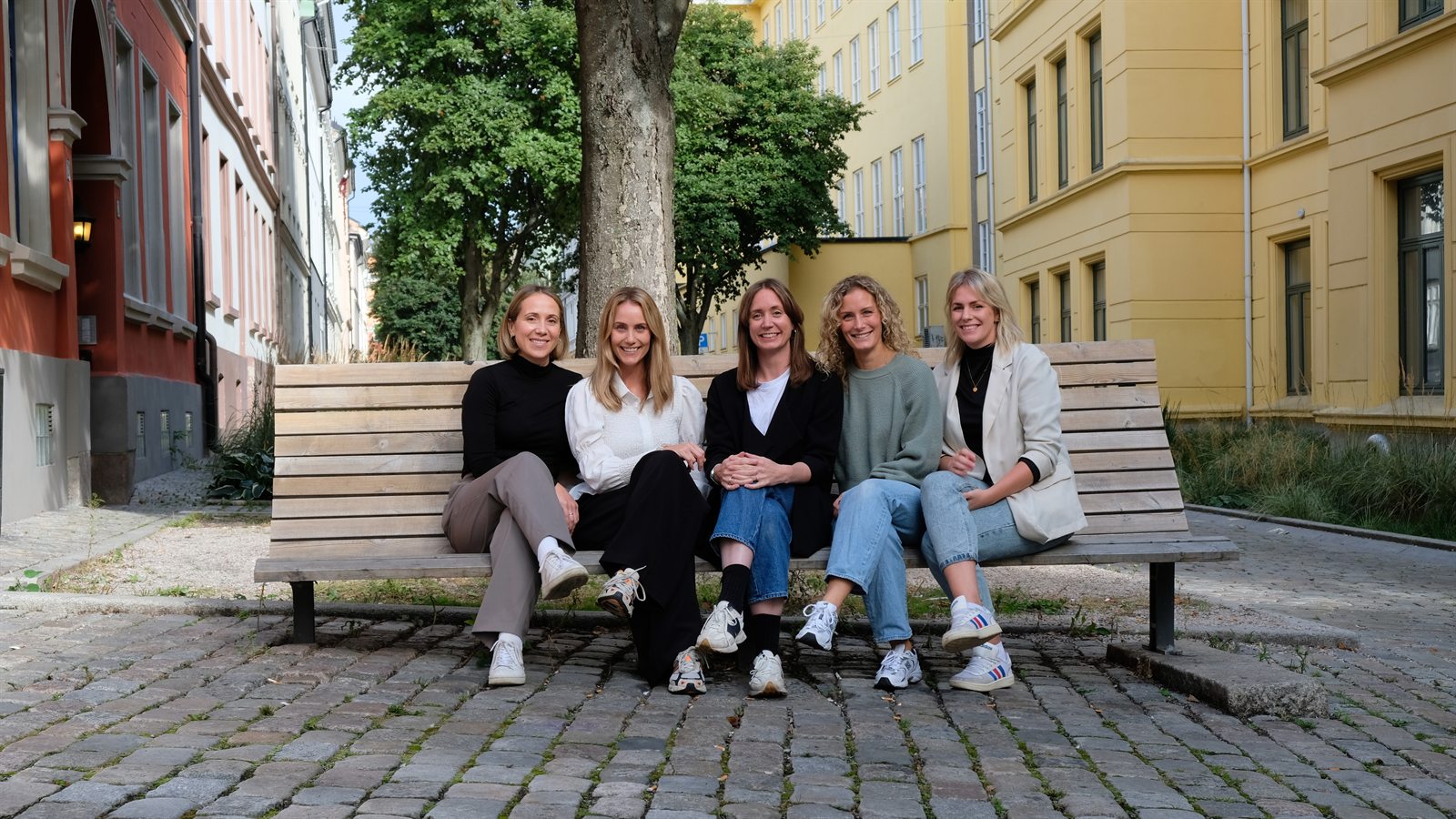 De fem logopedene i A-Logopedene sitter samlet på en benk i en gate i Oslo.